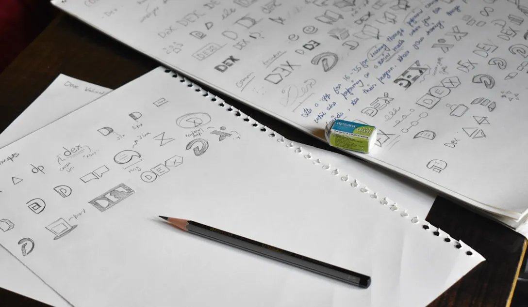 Logo sketches drawn in pencil across a sketchbook page