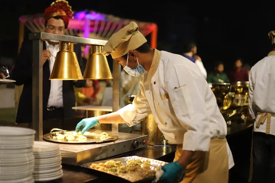 Catering trays being portioned on a steel bench in a commercial kitchen