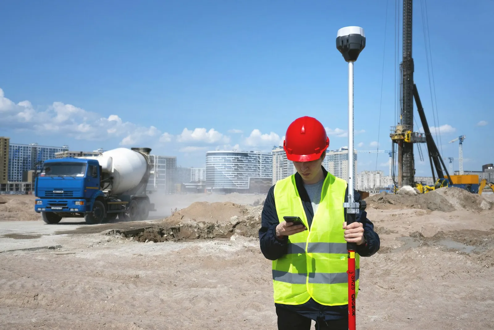 A site surveyor in a hi-vis vest holding a phone on a construction site