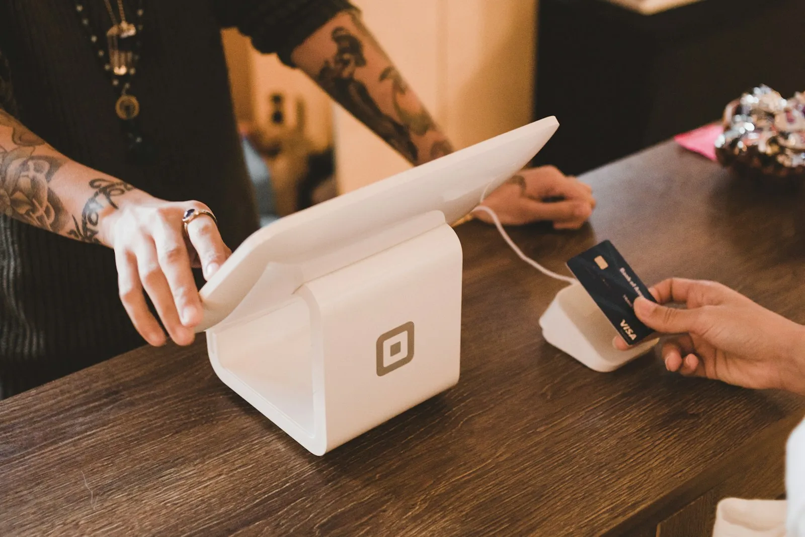 A bank card being tapped on a countertop payment terminal in a shop